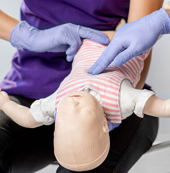 A healthcare professional demonstrating CPR on a child's manikin