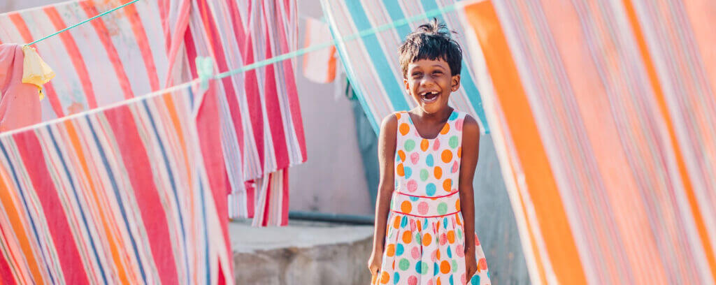 Sri Lankan girl standing among washing drying on a line smiling
