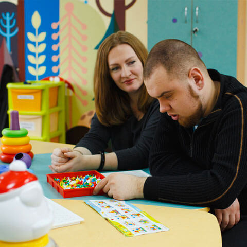 Support worker sat next to adult with learning disabilities