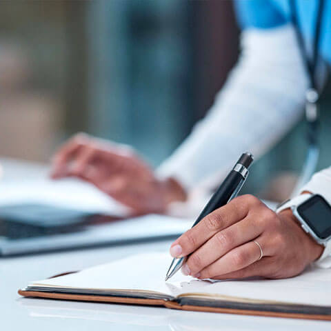 Health worker making notes while using a laptop