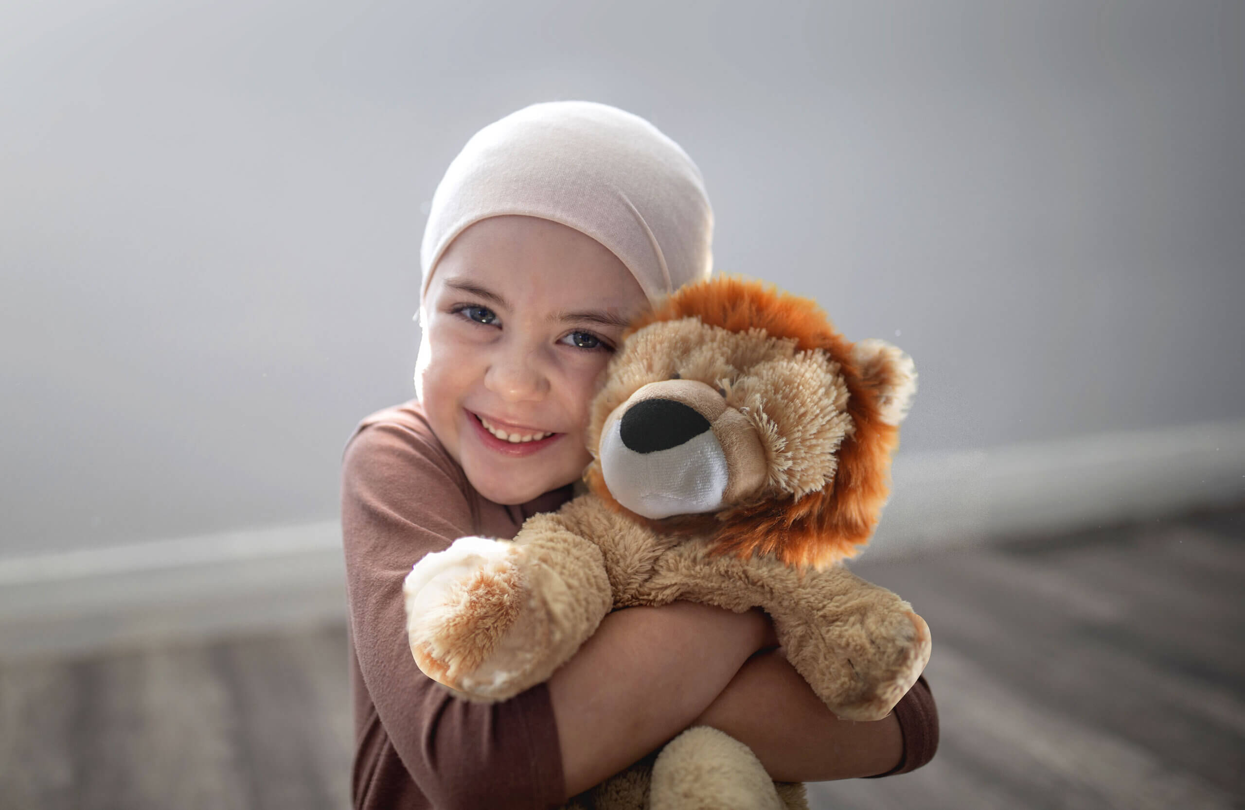 Child with happy face holding a soft toy called Joshua the Lion
